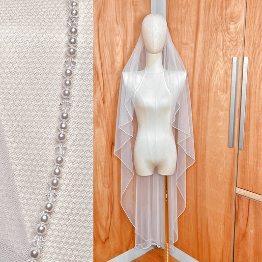 Front view of a waltz length angel cut wedding veil with a delicate pearl trim edge.