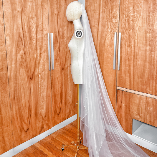 Side profile showing the cascading layers of a cathedral length wedding veil with beaded edges.