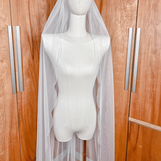 High-resolution detail of hand-sewn beads and crystals on a scalloped edge wedding veil.
