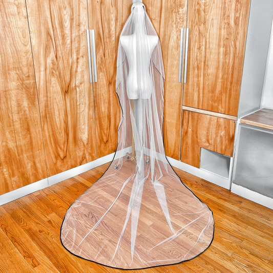 Rear view of a cascading cathedral length bridal veil featuring a bold black satin edge.