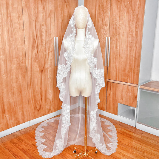 Front view of a cathedral length Chantilly lace bridal mantilla veil draped over a mannequin.