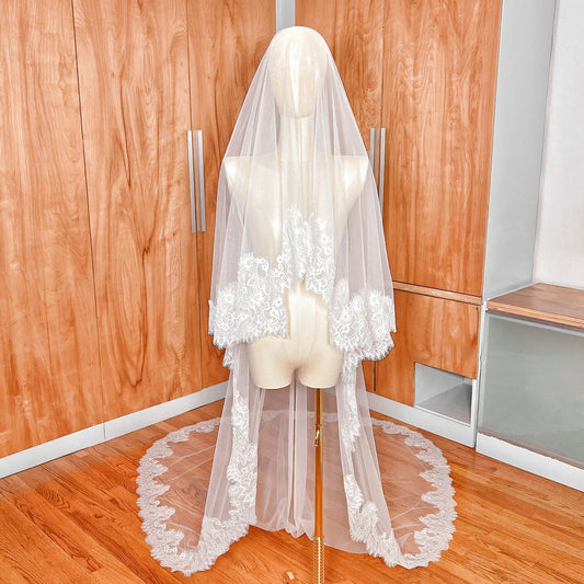 Front view of a Chantilly lace drop wedding veil with blusher covering the face of a mannequin.