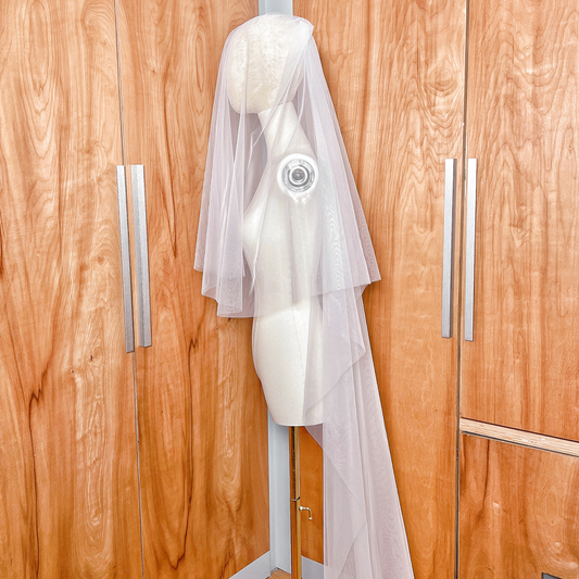 Side profile of a chapel length wedding veil with a blusher tier, highlighting the lightweight tulle and simple raw edge design.