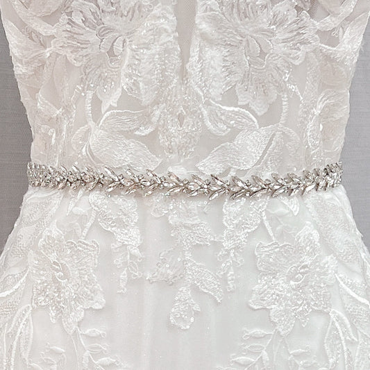 Close-up view of a silver beaded bridal belt and crystal rhinestone wedding dress sash displayed on a bridal mannequin.