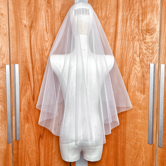A classic two tier elbow length bridal veil featuring a sheer blusher and minimalist raw edge.