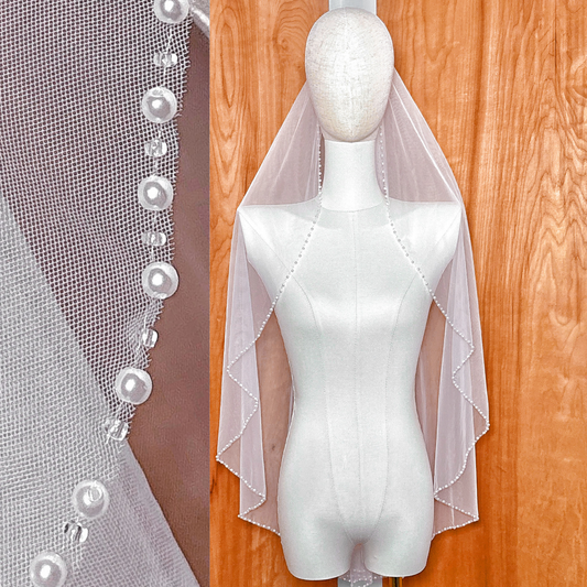 Ivory fingertip length wedding veil featuring a delicate pearl lined border and soft bridal tulle.
