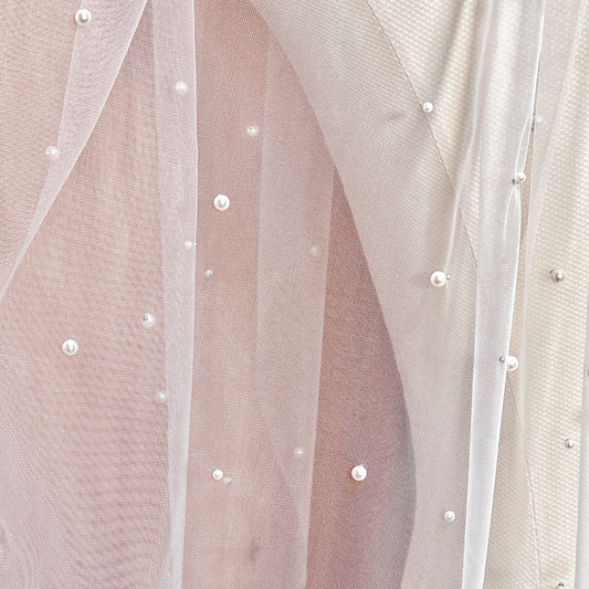 Close-up of the intricate scattered pearl embellishments on a fingertip-length wedding veil, highlighting the high-quality 4mm pearls and raw-edge finish.