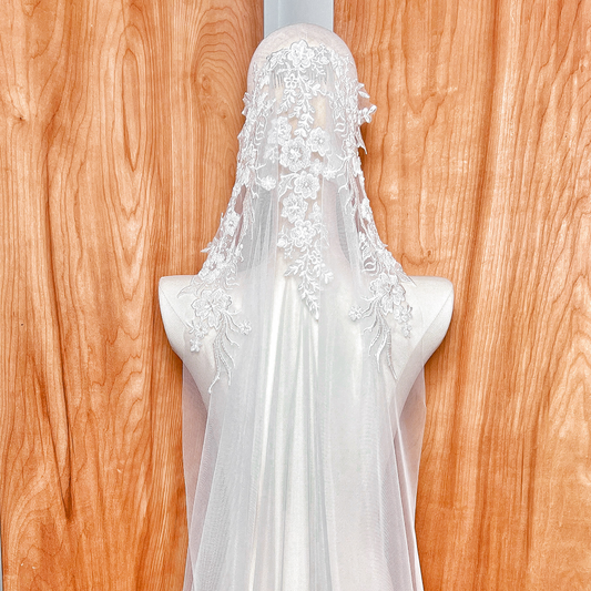 Macro shot of delicate beadwork and embroidery on a mantilla style wedding veil, highlighting the craftsmanship of the lace border.