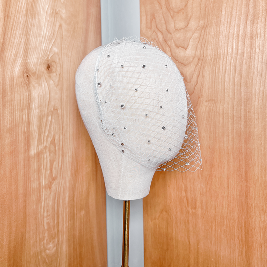 Side view of a luxury crystal birdcage wedding veil showing the French netting and sparkling embellishments on a bridal display.
