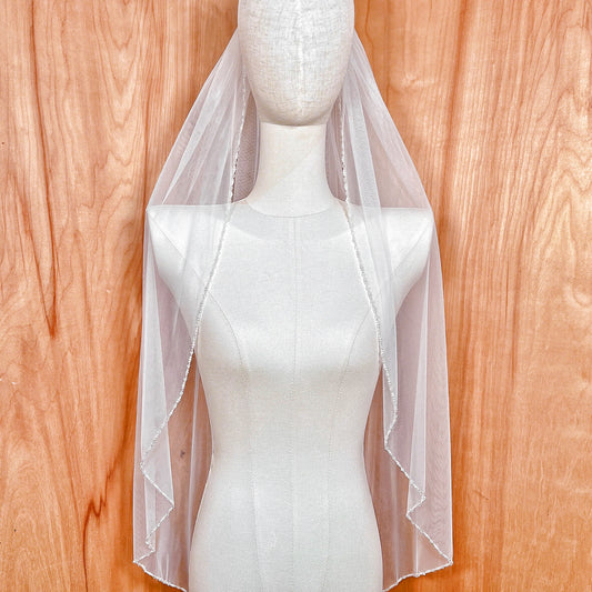 Fingertip length wedding veil featuring a delicate hand-sewn pearl and crystal beaded edge.