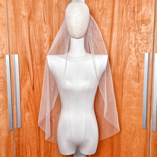 A delicate pearl cluster wedding veil in fingertip length featuring hand-placed ivory pearls scattered across soft bridal tulle.