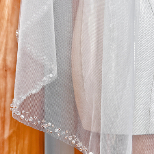 Fingertip length wedding veil with a detailed pearl and crystal beaded edge displayed on a bridal mannequin.