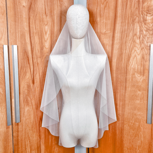 Soft ivory tulle texture of the raw edge cascade wedding veil showing its sheer quality.