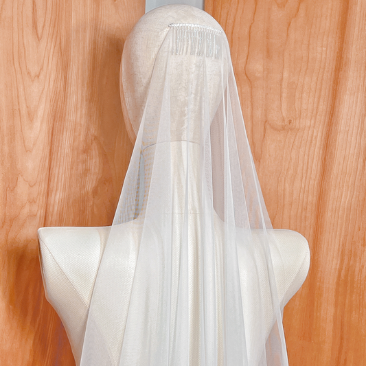 Close-up of a sheer minimalist wedding veil in fingertip length with a classic raw edge design.