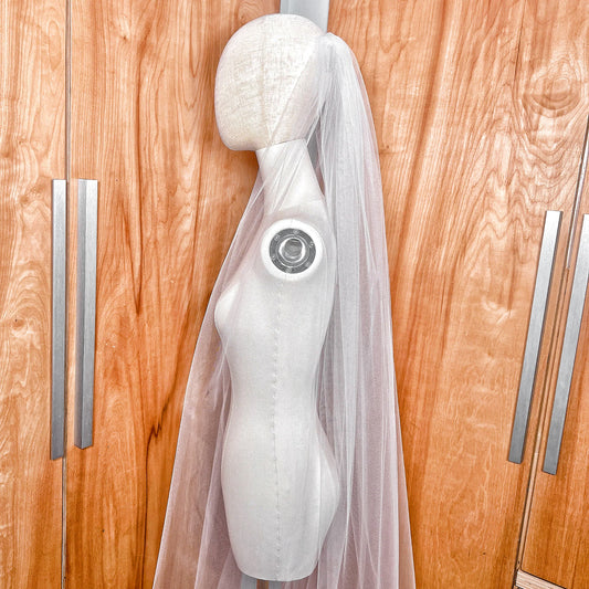 Detailed close-up of the delicate raw edge on a sheer ivory chapel length tulle bridal veil.