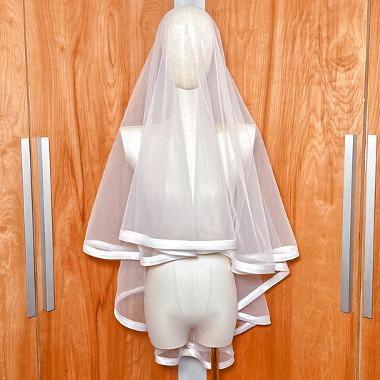 Front view of a fingertip length bridal veil with a one-inch ribbon edge and blusher displayed on a mannequin.