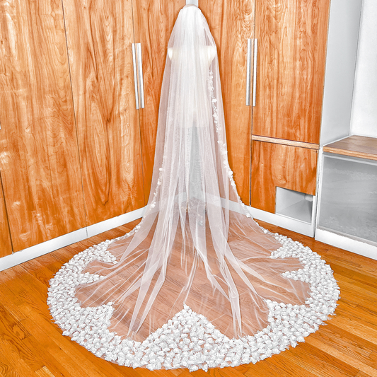 Full view of the long sweeping train of a romantic 3D flower wedding veil in cathedral length shown on a bridal mannequin.