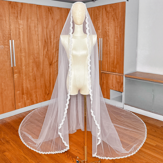 Full front view of a royal cathedral length beaded mantilla wedding veil draped over a mannequin to show the lace framing the face.