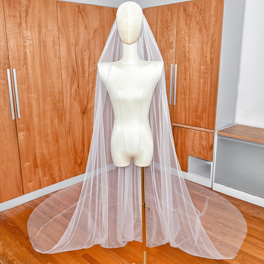 Full-length view of a Royal Cathedral Tulle Wedding Veil with a clean raw edge flowing from a mannequin.