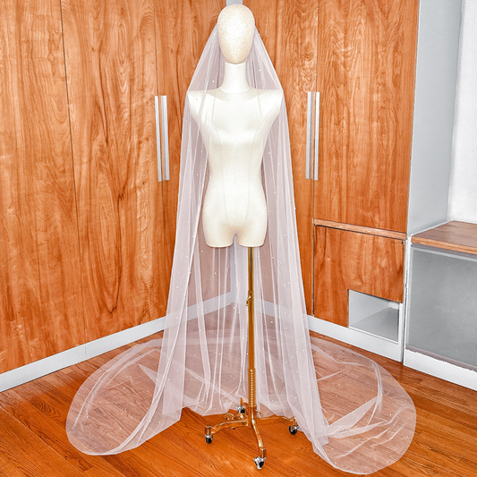 A full-length view of a 118-inch cathedral wedding veil featuring elegantly scattered pearls on ivory tulle.