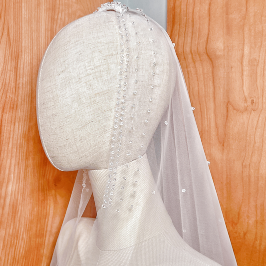 Side profile of a mannequin wearing the fingertip-length Crystal Edge Mantilla Wedding Veil, highlighting the elegant drape and crystal trim.