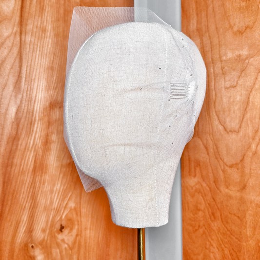 Side profile of a tulle bandeau wedding veil with rhinestones demonstrating the drape and fit on a bridal display.