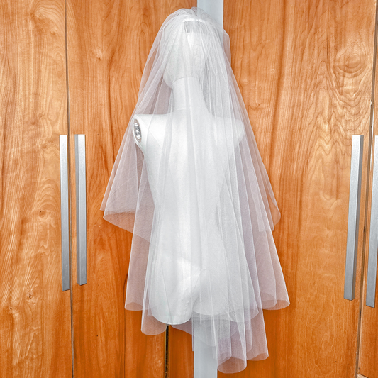 Side profile of a voluminous two tier fingertip length blusher veil on a mannequin showing layered tulle volume.