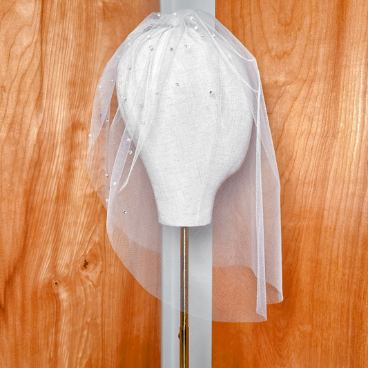 Side profile view showing the scheduling drape of the tulle birdcage wedding veil with rhinestones and pearls.