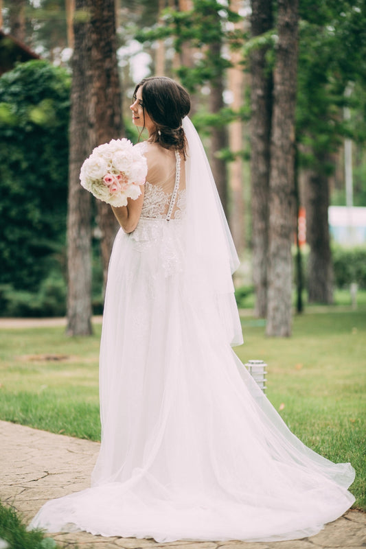 Two-tier fingertip length wedding veil with the blusher layer folded back for a voluminous layered look.
