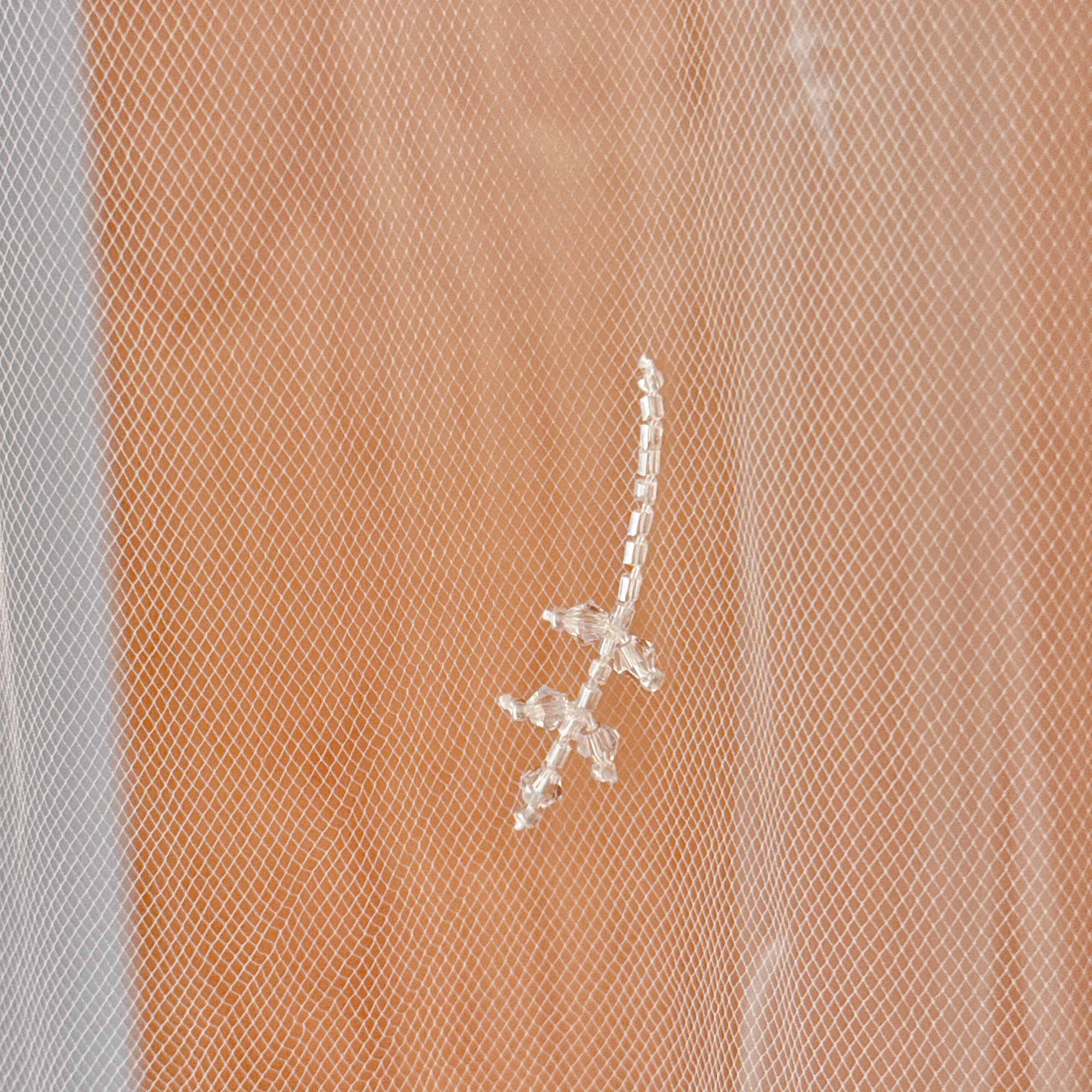 Close-up detail of 3D floral embroidery and shimmering crystals on a white bridal veil.