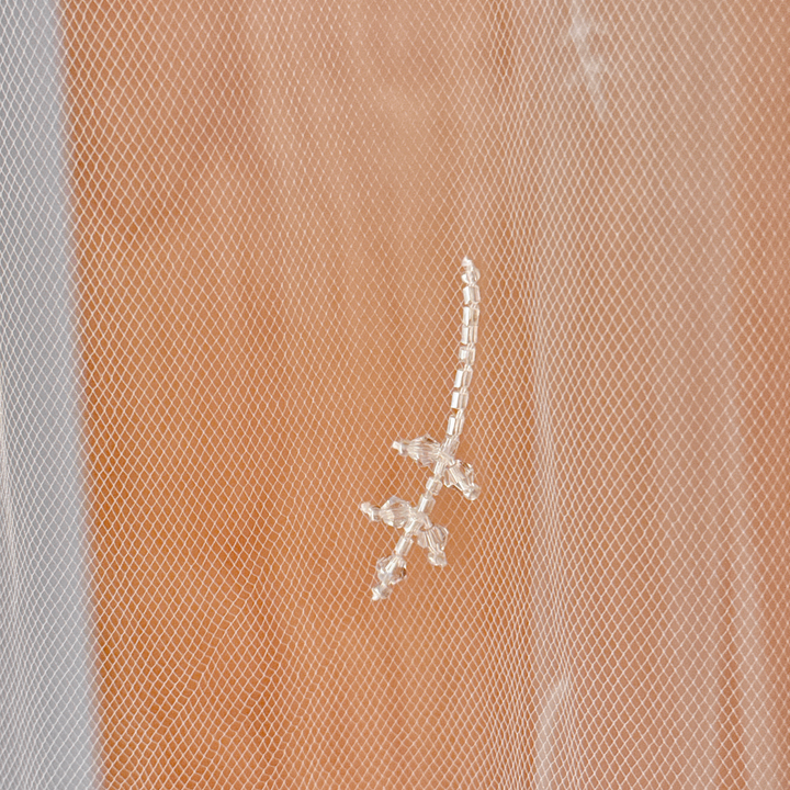 Close-up detail of 3D floral embroidery and shimmering crystals on a white bridal veil.