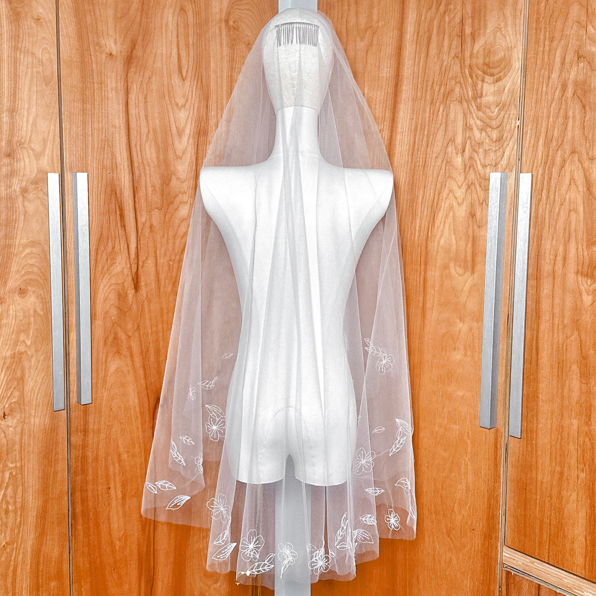 Back profile of a hand-embroidered 3D flower veil on a mannequin to show drape and floral placement.