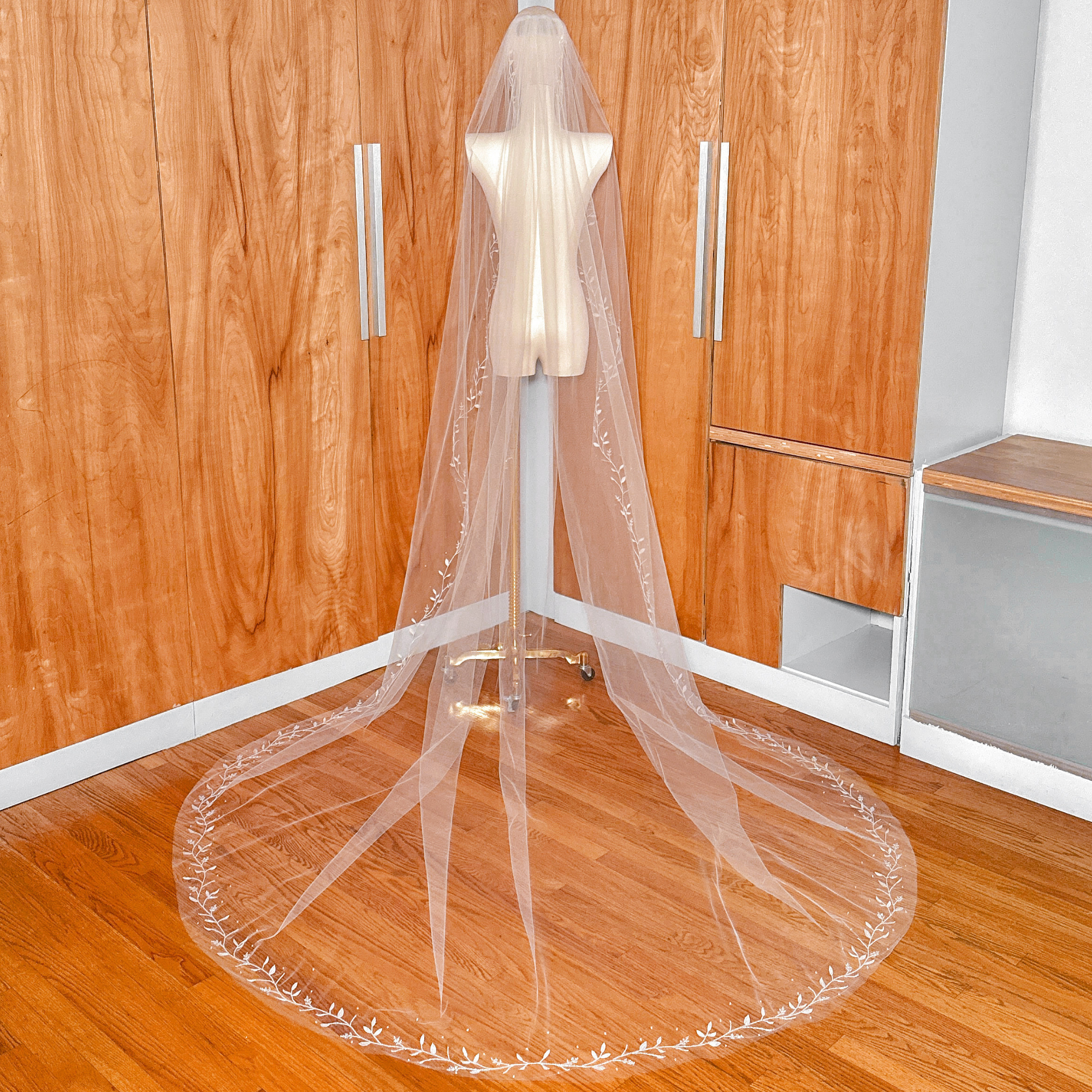Back view of the long cathedral train of a 3D silk leaf veil on a mannequin.