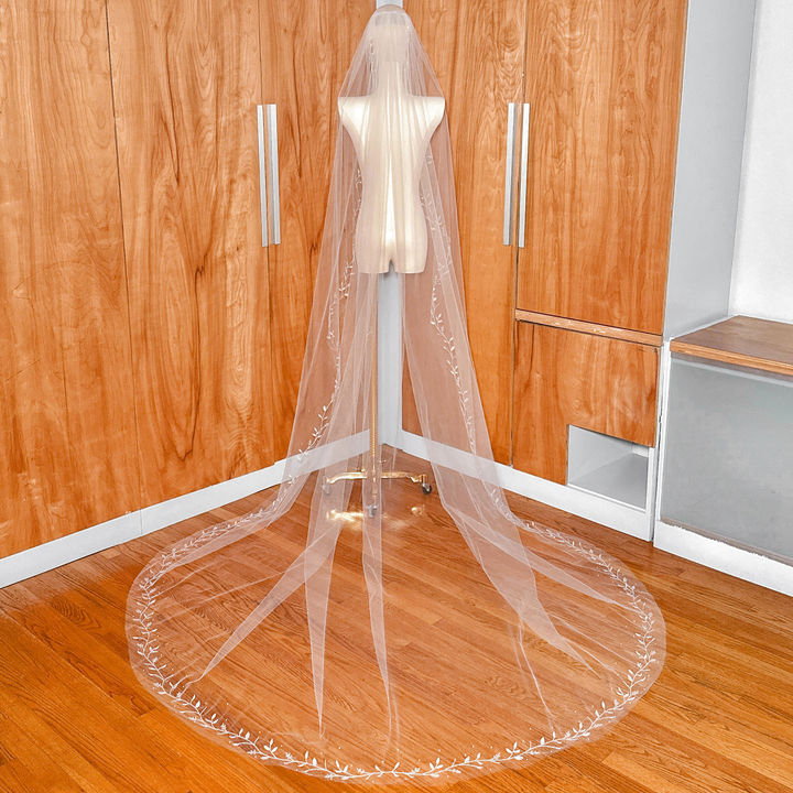 Back view of the long cathedral train of a 3D silk leaf veil on a mannequin.