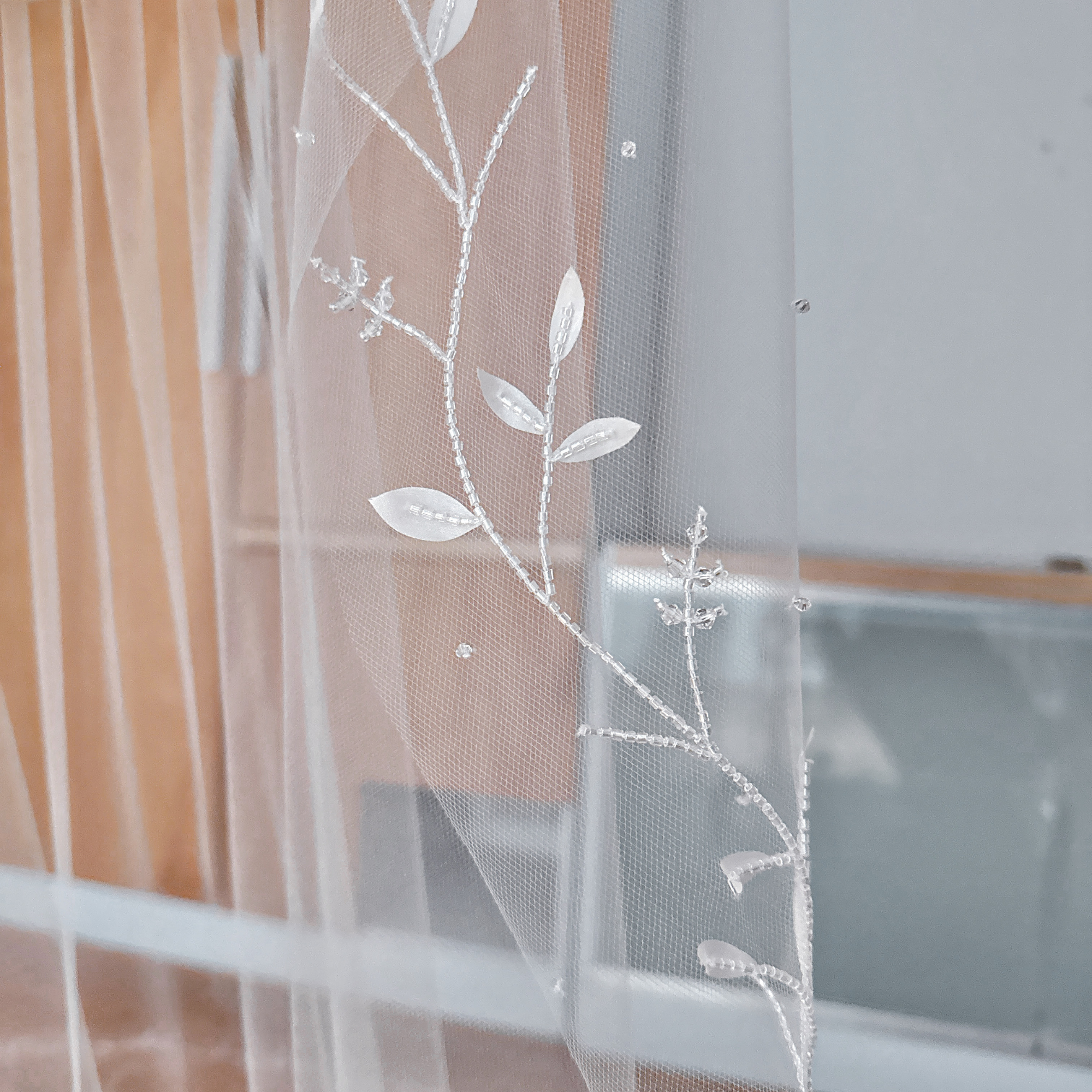 Side profile view of a 3D silk leaf wedding veil highlighting the beaded vine trim.