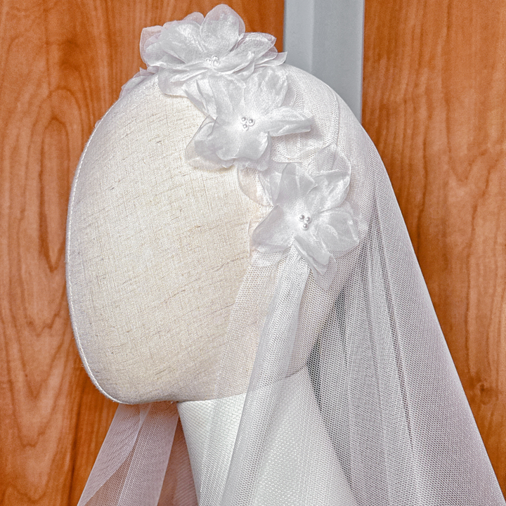 Mannequin display of a 60-inch waltz length Juliet cap veil embellished with silk organza floral accents.