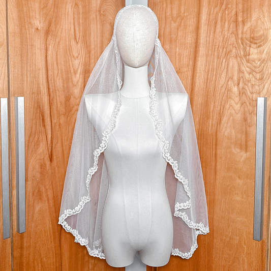 Alençon lace Juliet cap veil in fingertip length displayed on a bridal mannequin.