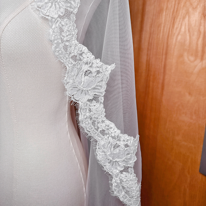 Close-up of the scalloped Alençon lace trim on a white bridal mantilla veil.