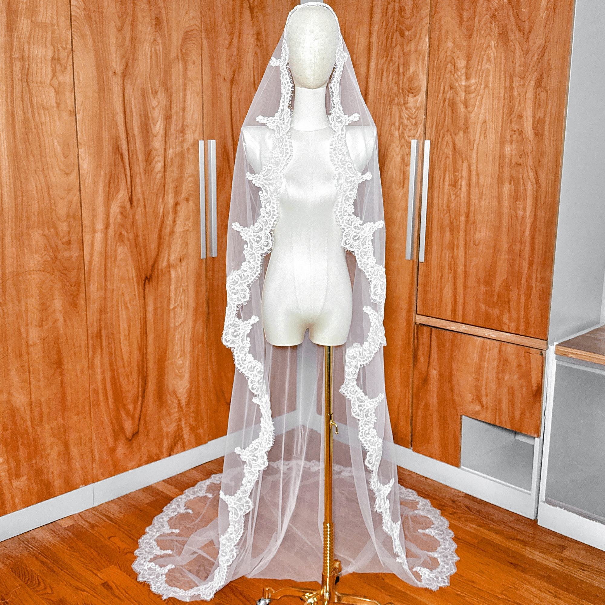 Front view of a cathedral length Alençon lace mantilla wedding veil draped over a mannequin's head.