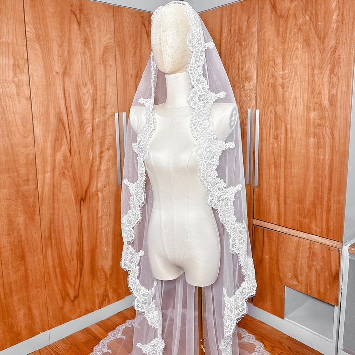 Side profile of a long cathedral Alençon lace mantilla veil on a mannequin showing the elegant drape.