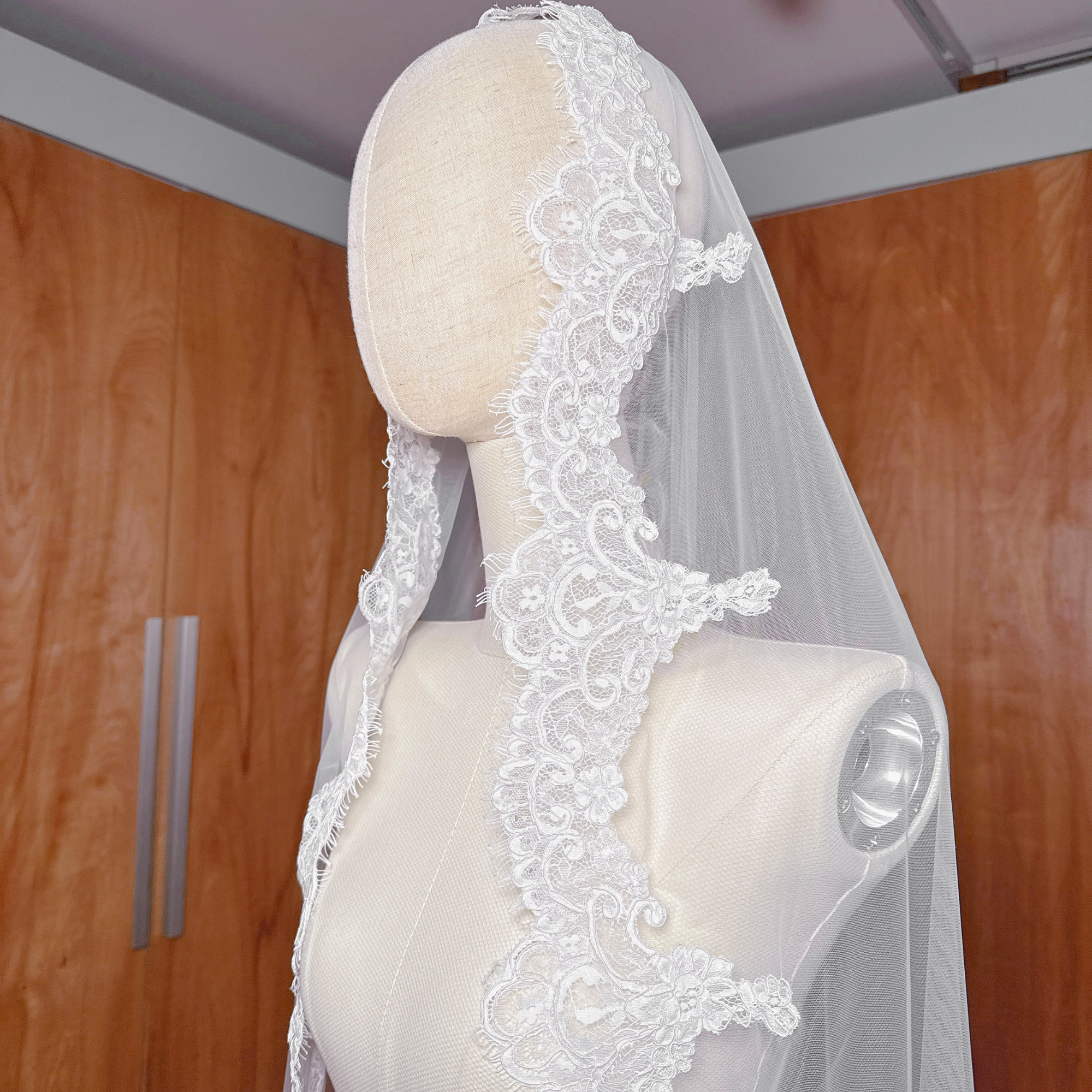 Overhead view of an ivory Alençon lace mantilla wedding veil showing the cathedral length tulle.