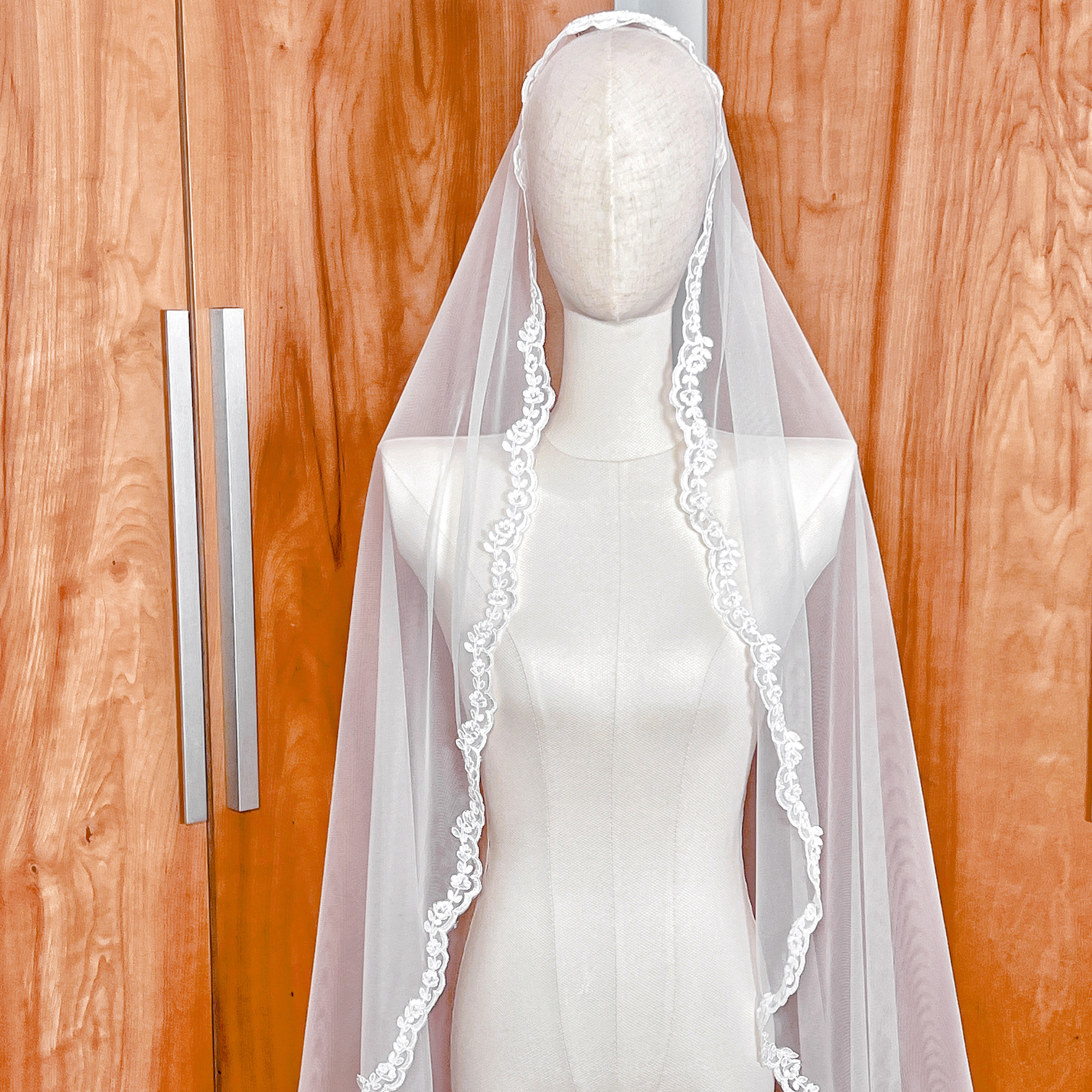 Close-up of the delicate floral embroidery and scalloped border on an Alençon lace mantilla wedding veil.