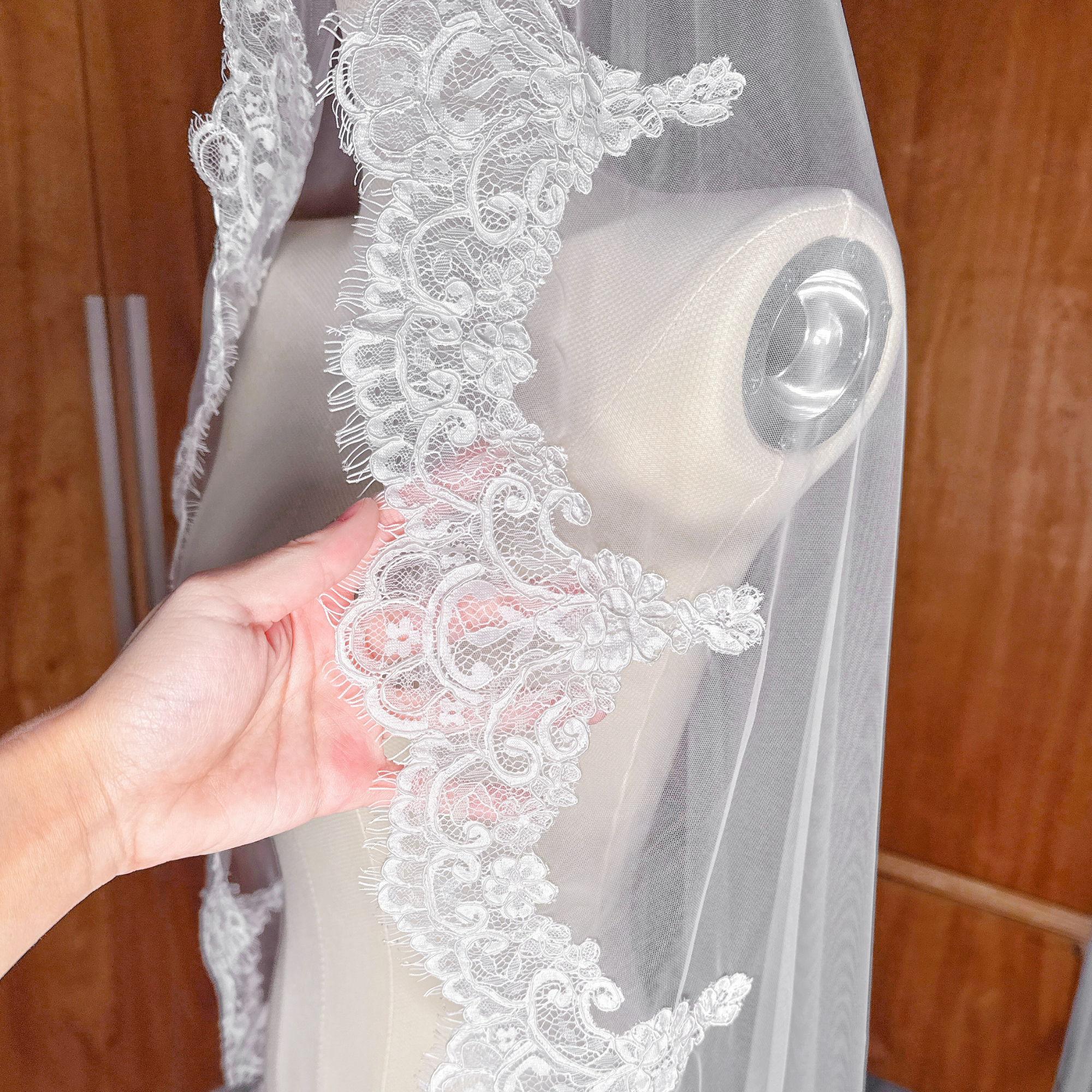Close-up detail of the intricate scalloped Alençon lace trim on a mantilla style wedding veil.