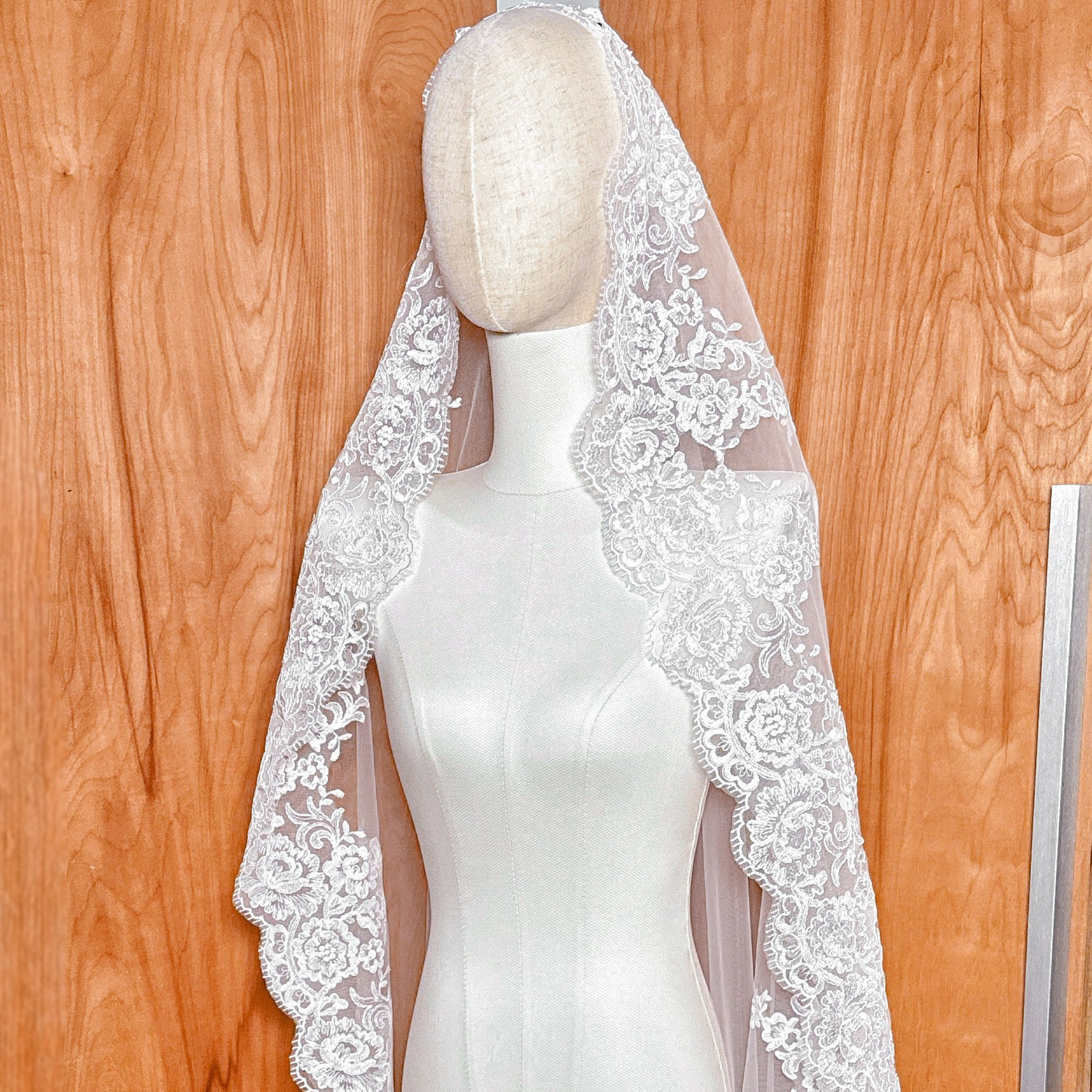 Top view of the Alençon lace mantilla wedding veil showing the comb attachment and lace placement.