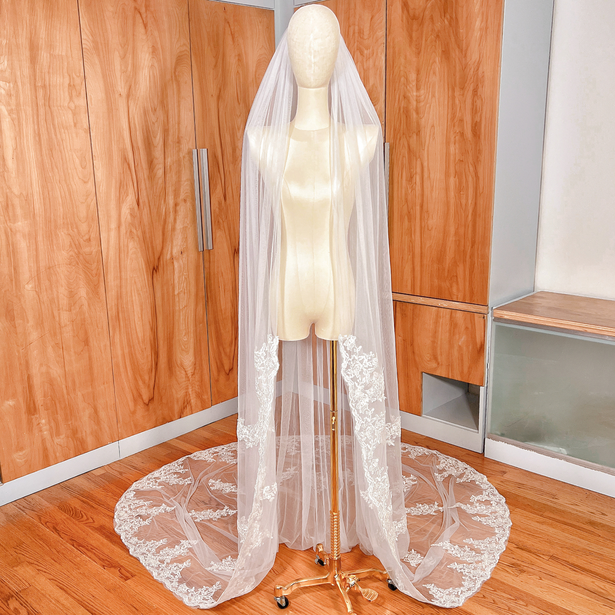 Cathedral length Alençon lace wedding veil draped elegantly on a mannequin, showcasing the intricate scalloped lace trim and flowing tulle.