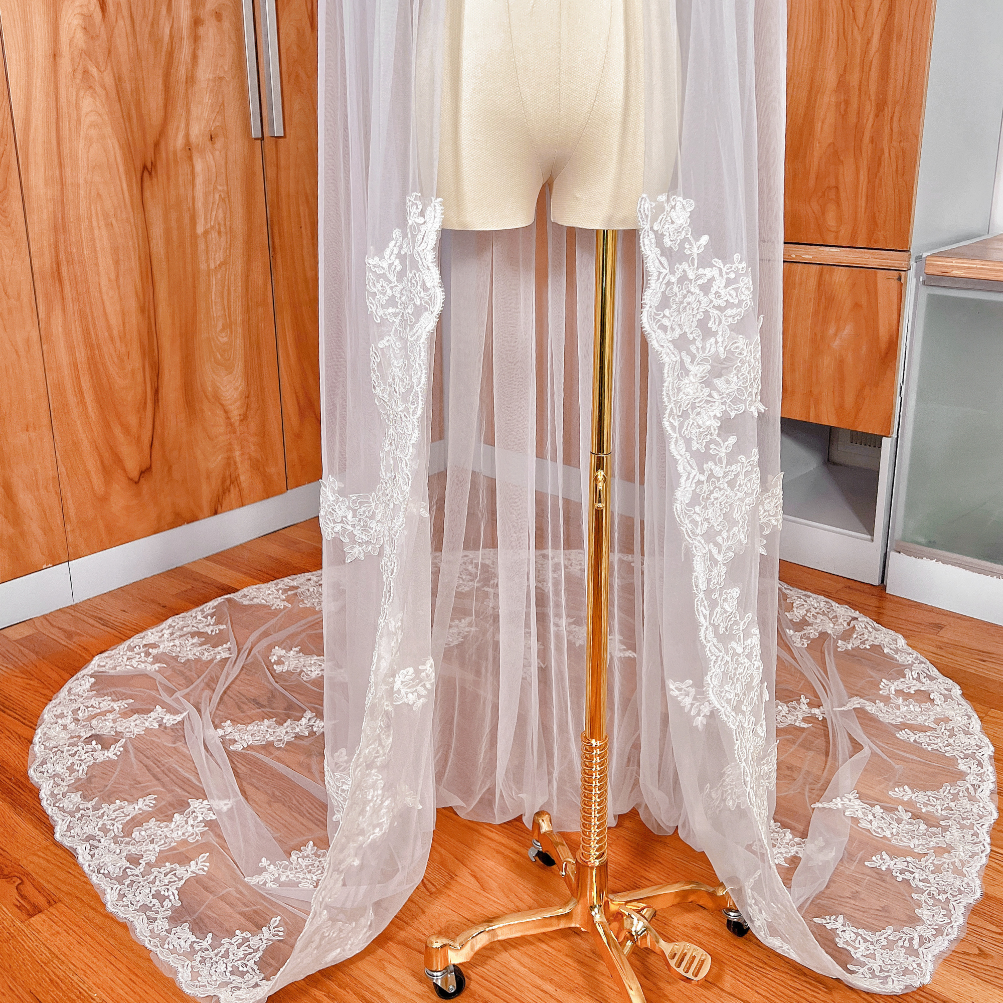 A close-up view of the fine French Alençon lace embroidery on the edge of the cathedral length wedding veil, displayed on a mannequin.