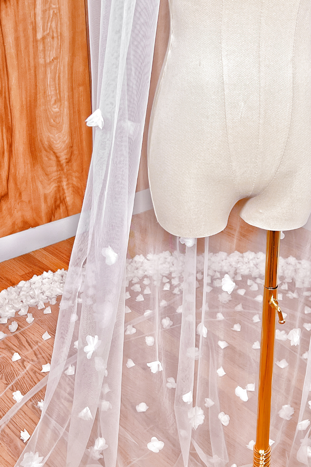 Side profile of an allover 3D floral cathedral length veil draped over a white bridal mannequin.