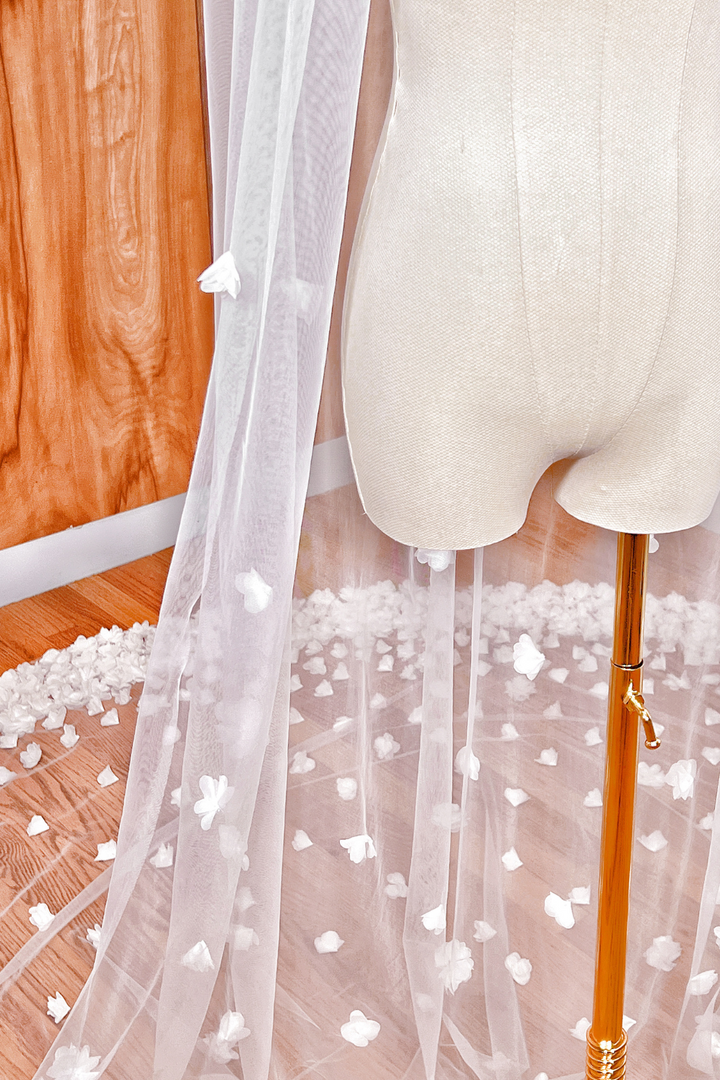 Side profile of an allover 3D floral cathedral length veil draped over a white bridal mannequin.