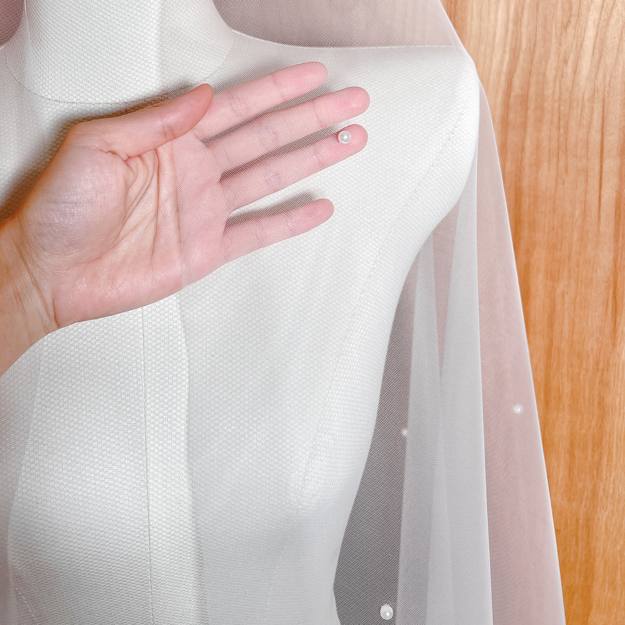 Close-up detail of scattered pearls on an allover pearl wedding veil with a long, cathedral length train.