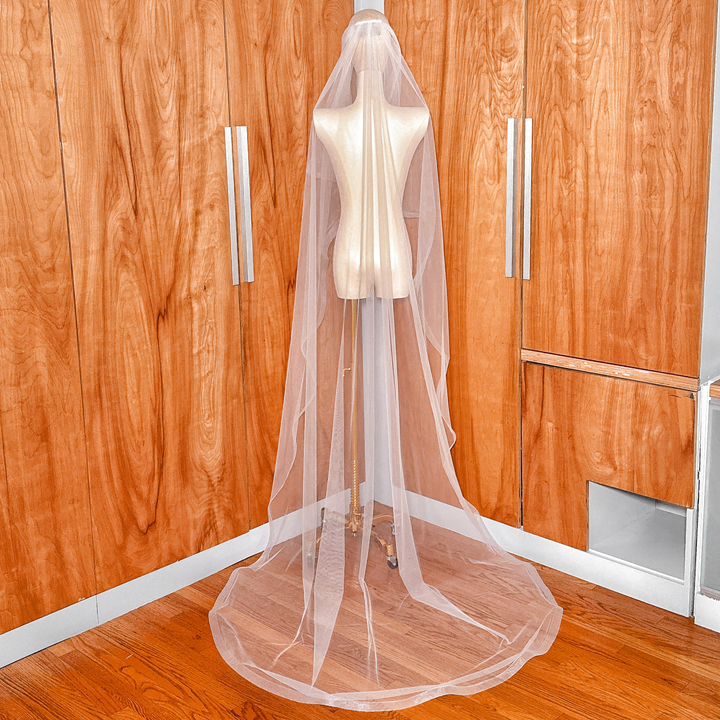 Back view of an angel cut cathedral wedding veil with a structured 1-inch horsehair trim draped over a mannequin.